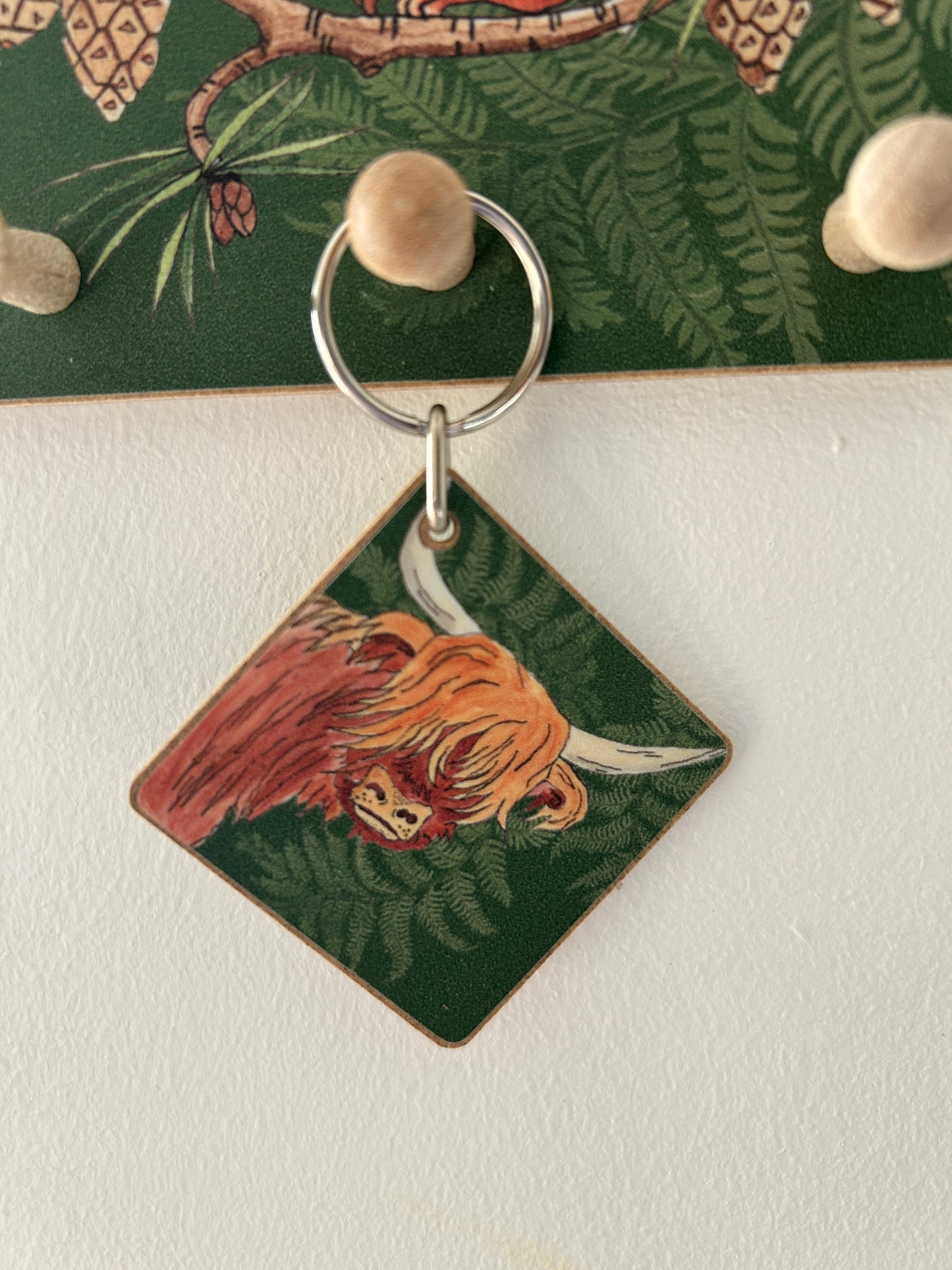 Highland cow illustration on a wooden keyring hanging from peg hook