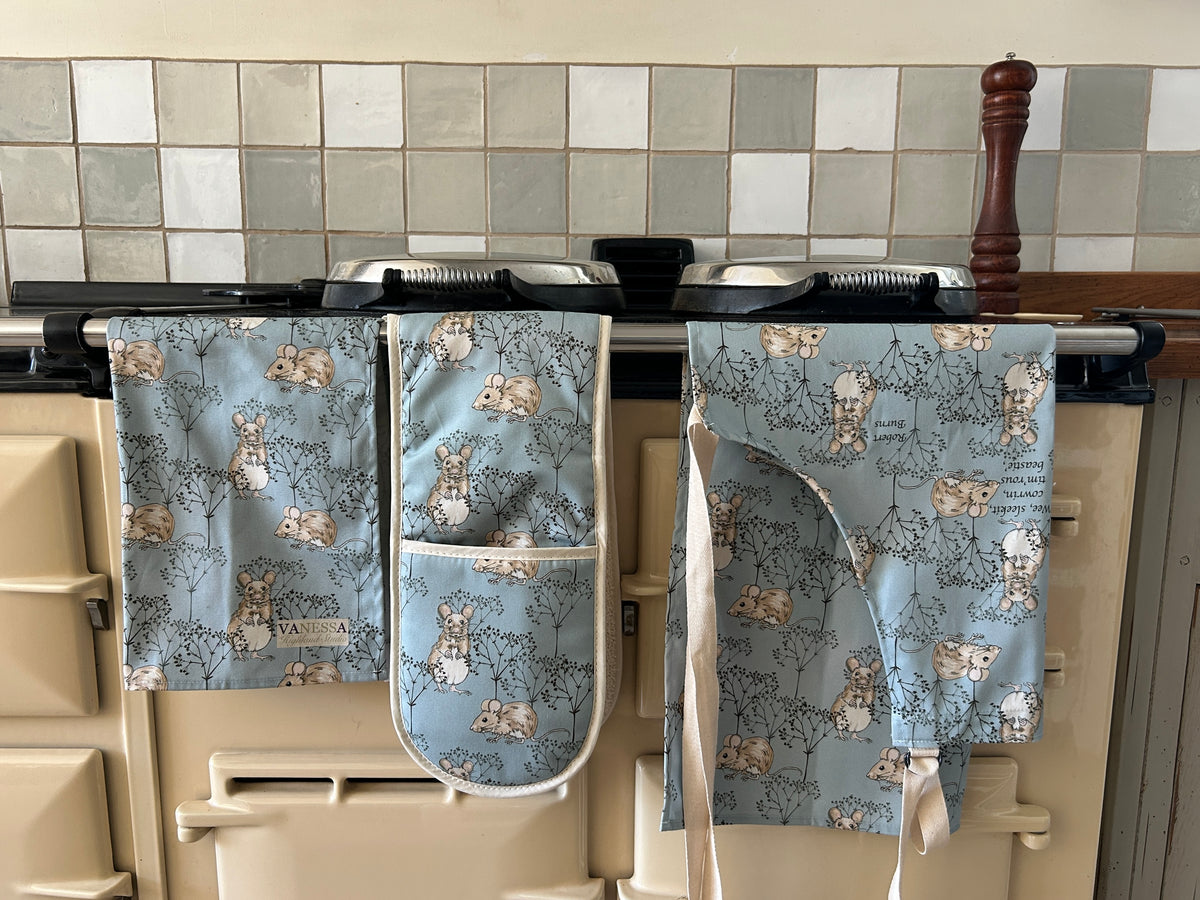 Tea towel, oven glove and apron in a mouse and twig design with blue background, hanging on an AGA cooker