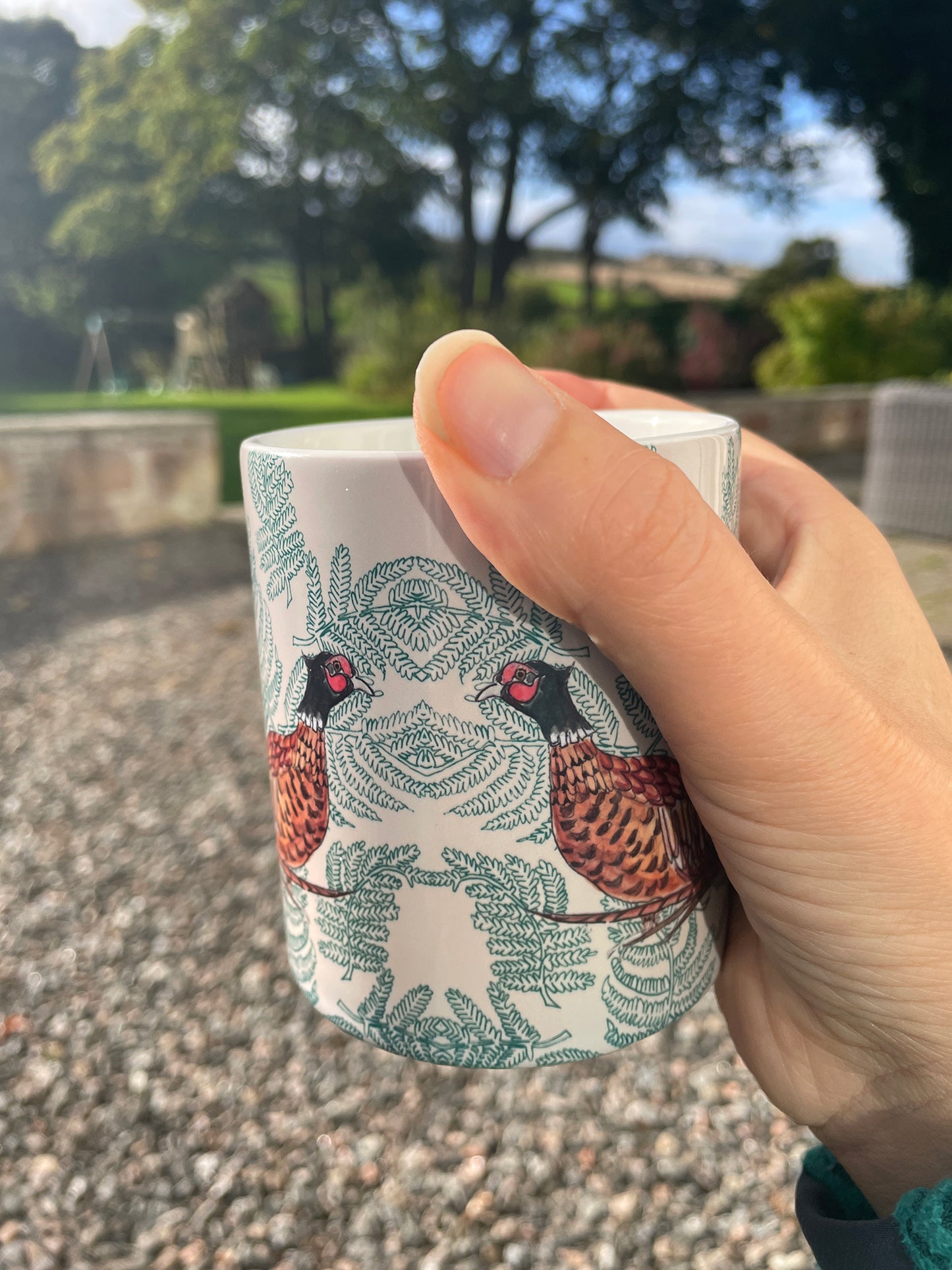 ceramic mug with pheasant fern design , held in an hand