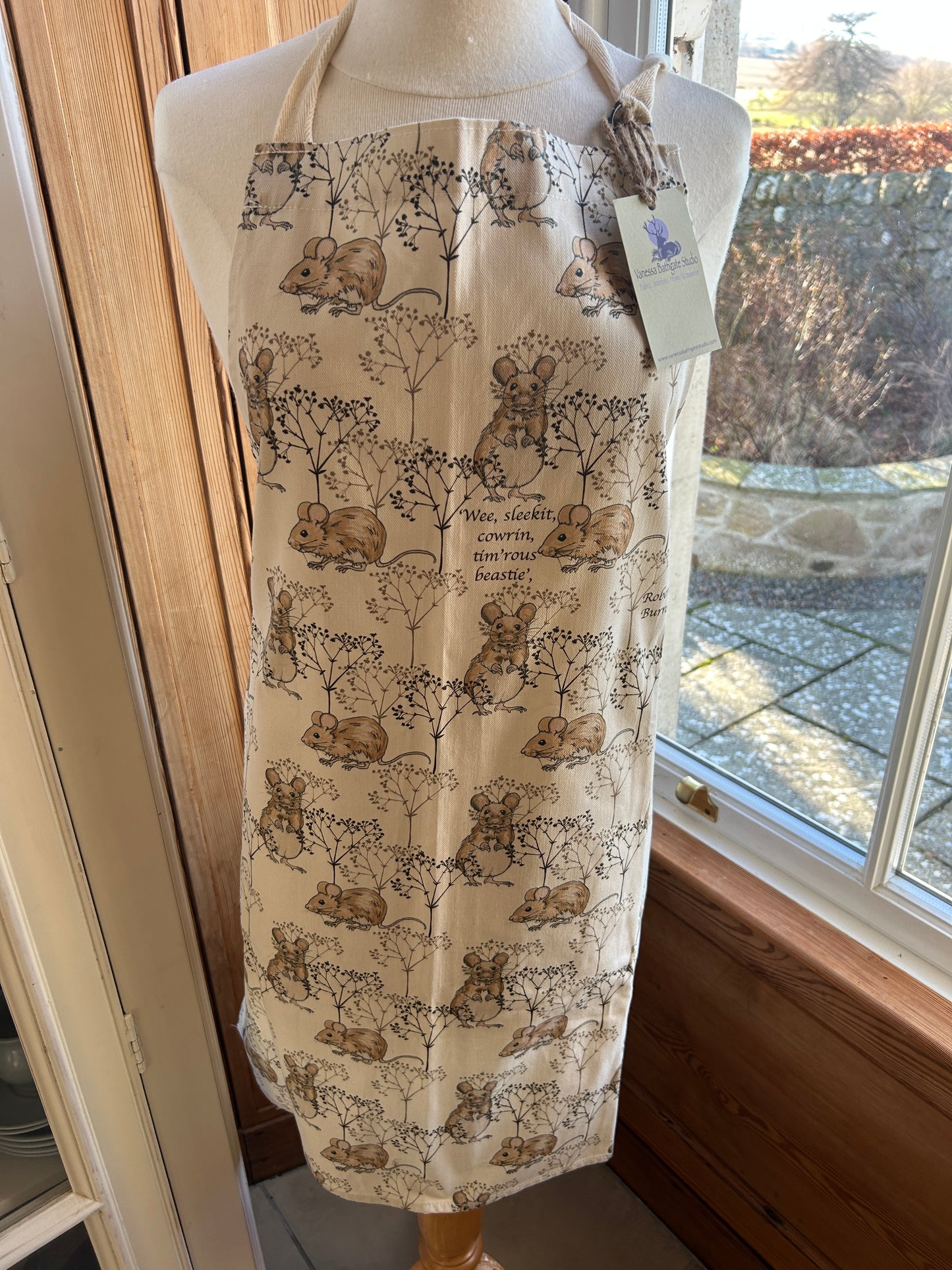 White apron featuring Vanessa Bathgate Mouse and twig design.