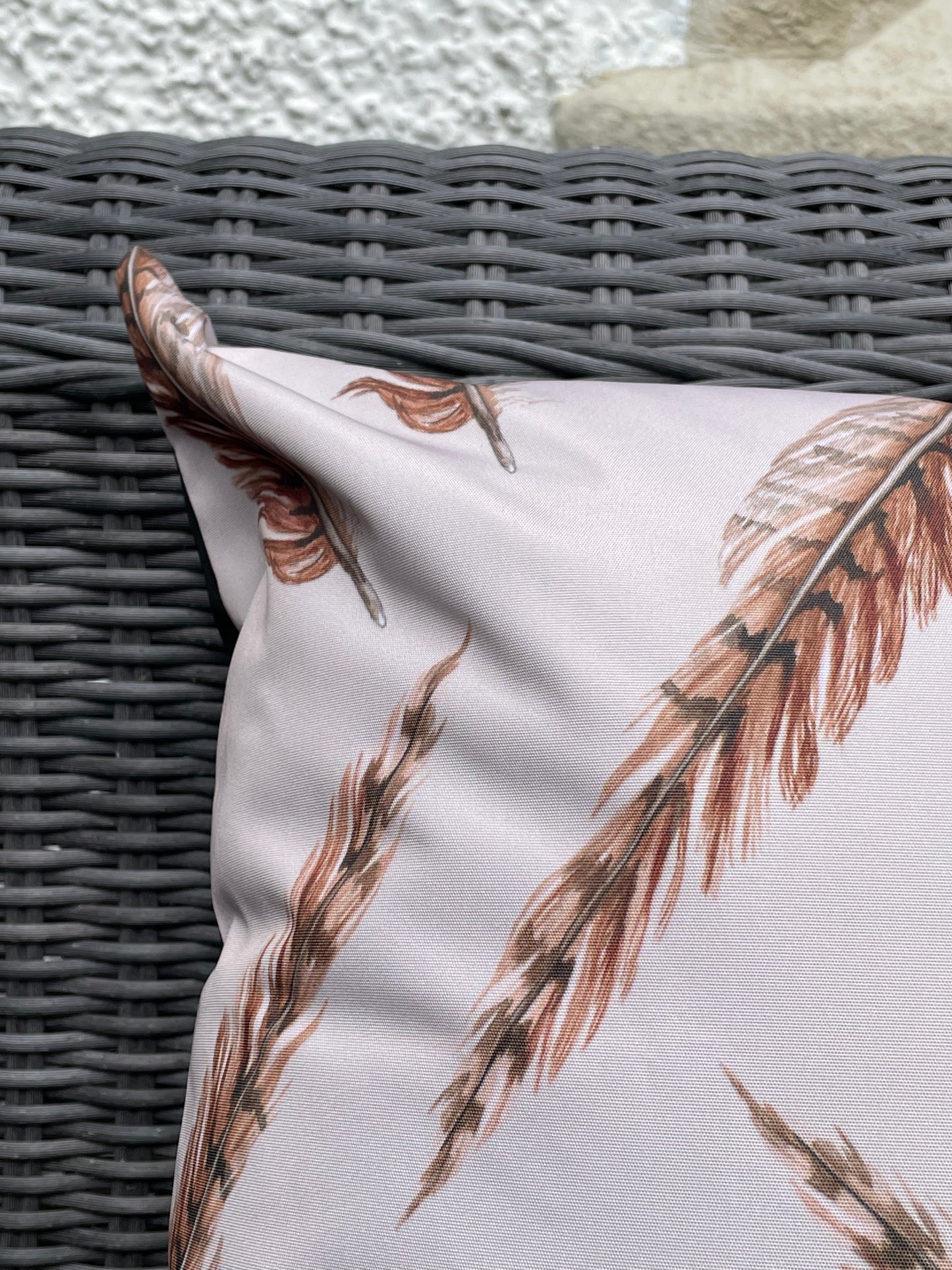 Close up image of pheasant feather illustration design on an outdoor, water repellent cushion. Cream background