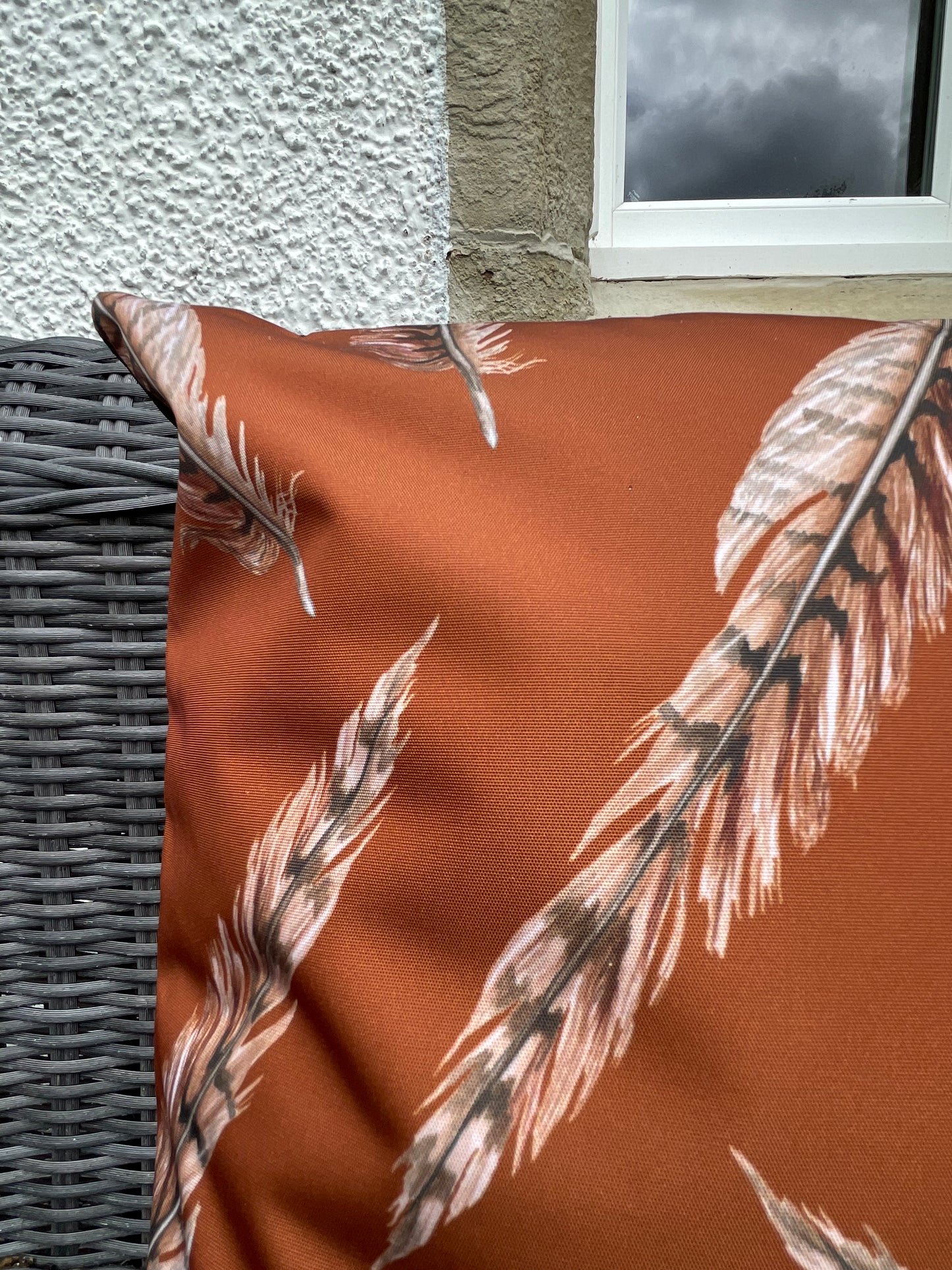 Close up of pheasant feather, illustration design on water repellent outdoor cushion. Rust colour background