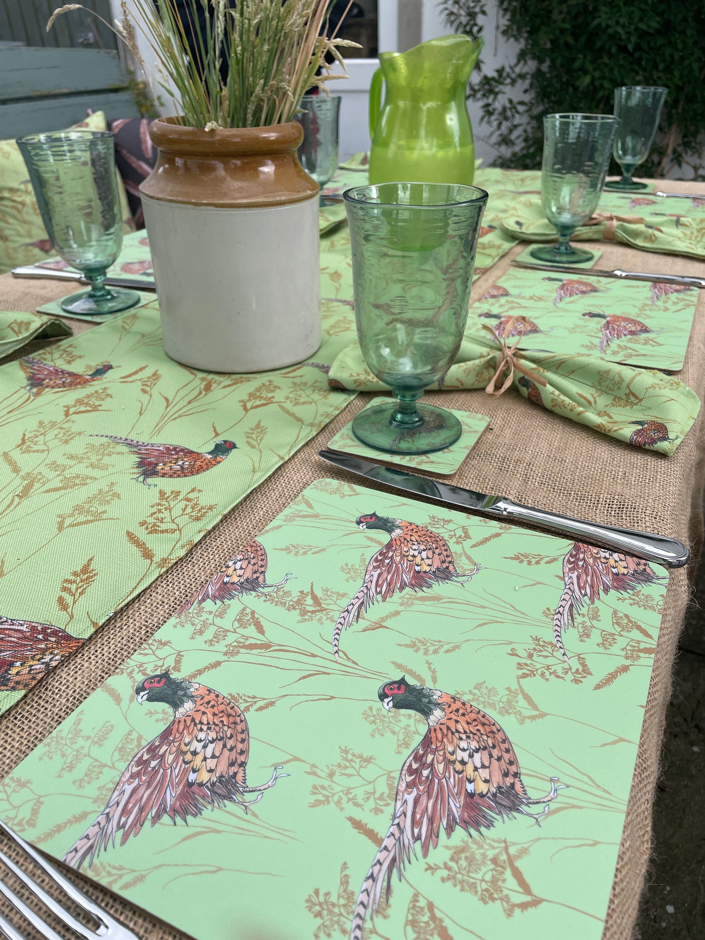 Pheasant design in lime, table mats, runner and napkins displayed an outdoor picnic setting