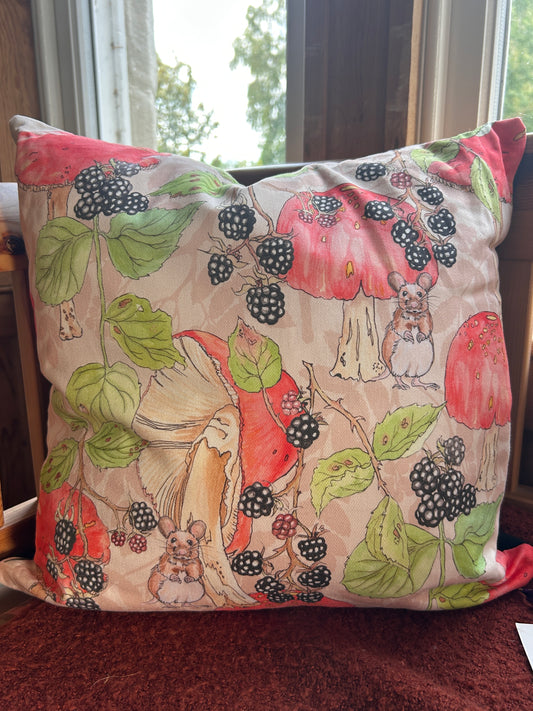A square cushion with a illustration print featuring blackberries, mushrooms, leaves, and small mice on a light beige background