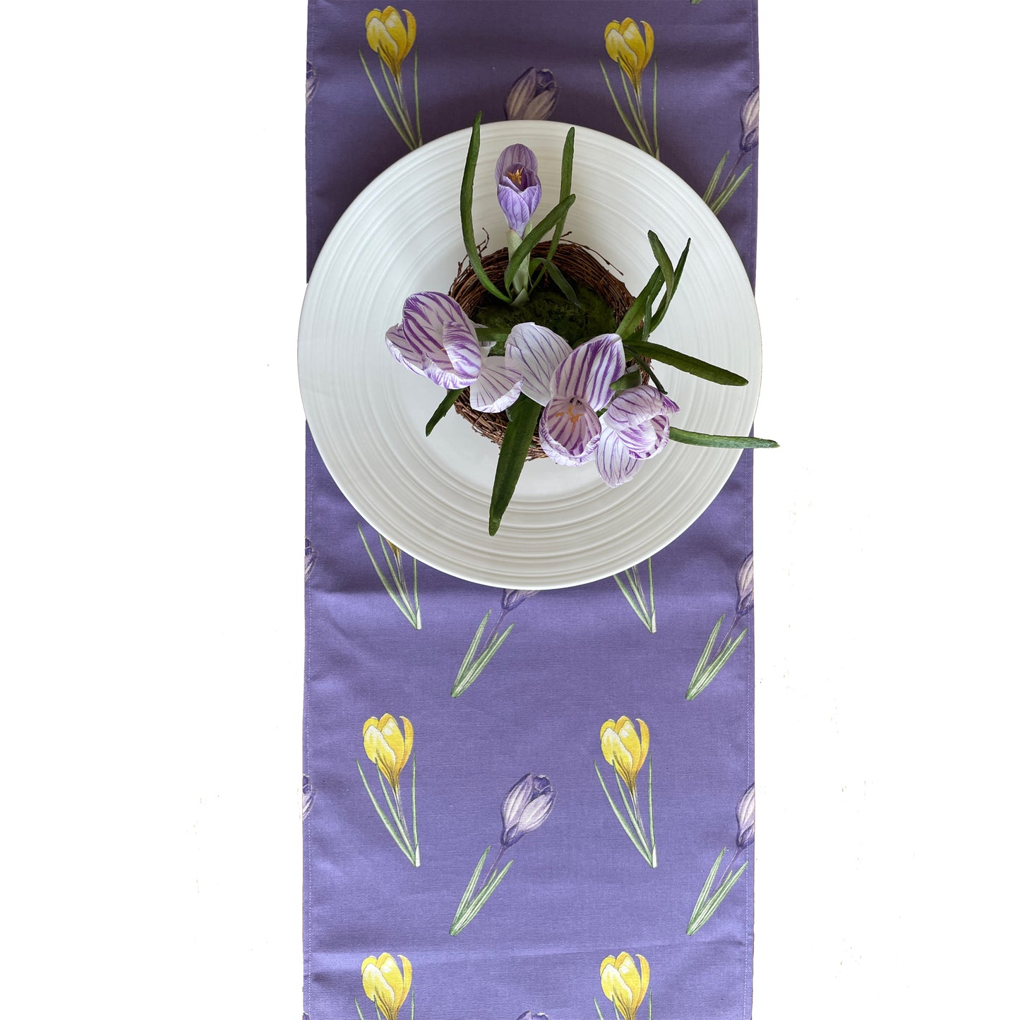 aerial shot of pacesetting. White dinner plate with crocuses and crocus design table runner
