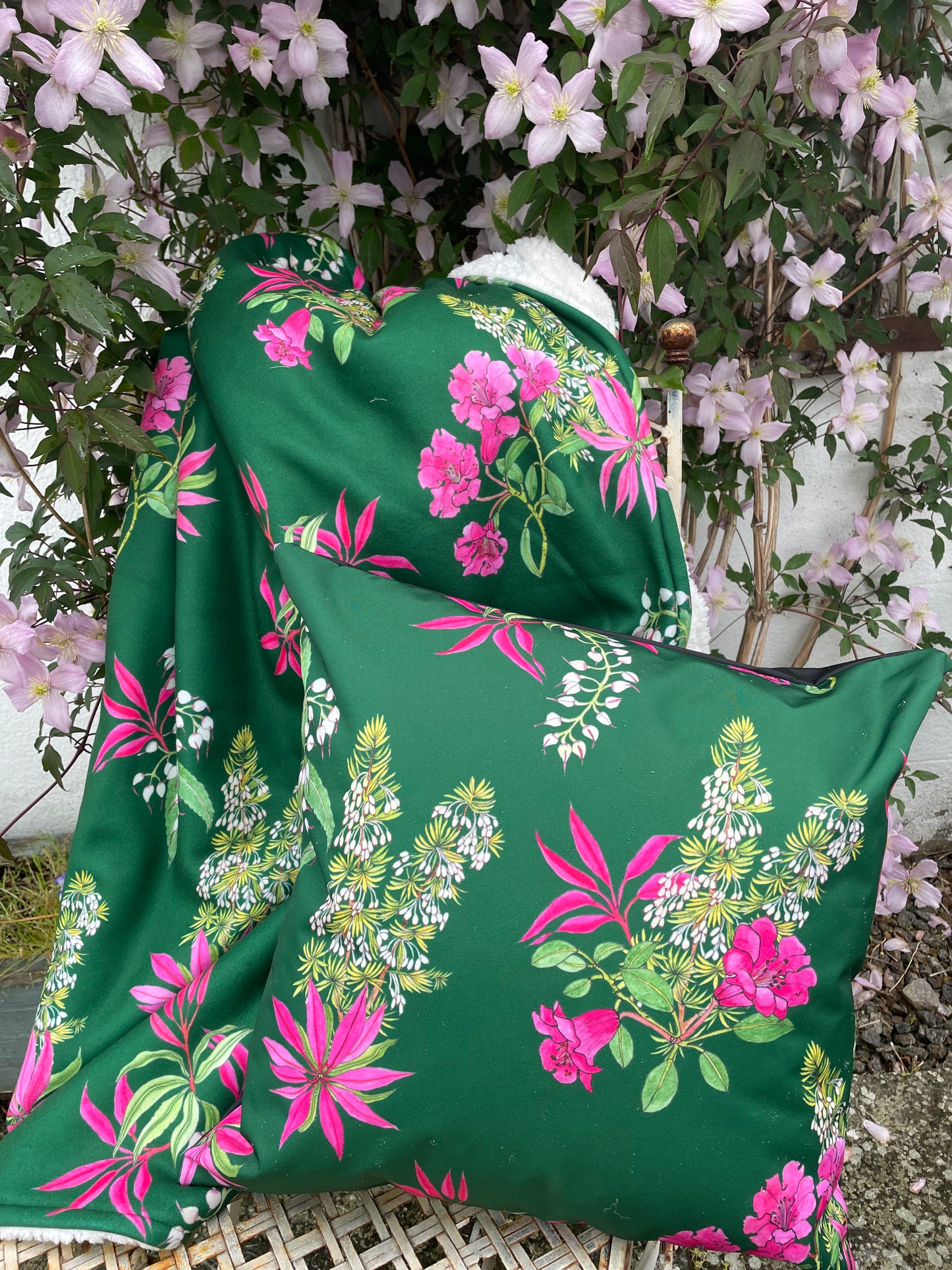 Outdoor cushion with matching fleece throw. In dark green background with bright pink, Rhododendron print