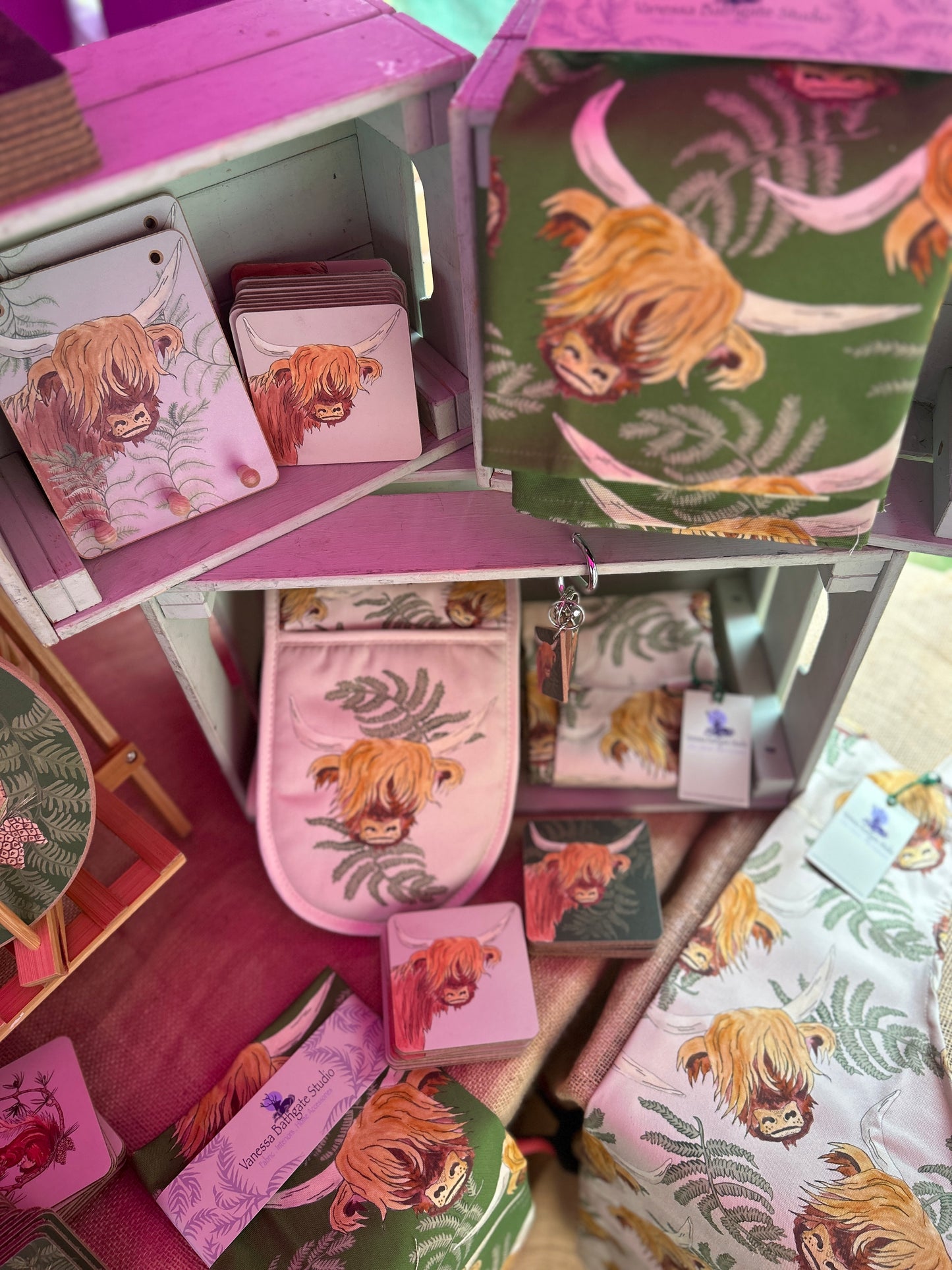 Highland cow design kitchen pieces in a display. coasters, oven gloves, tea towels