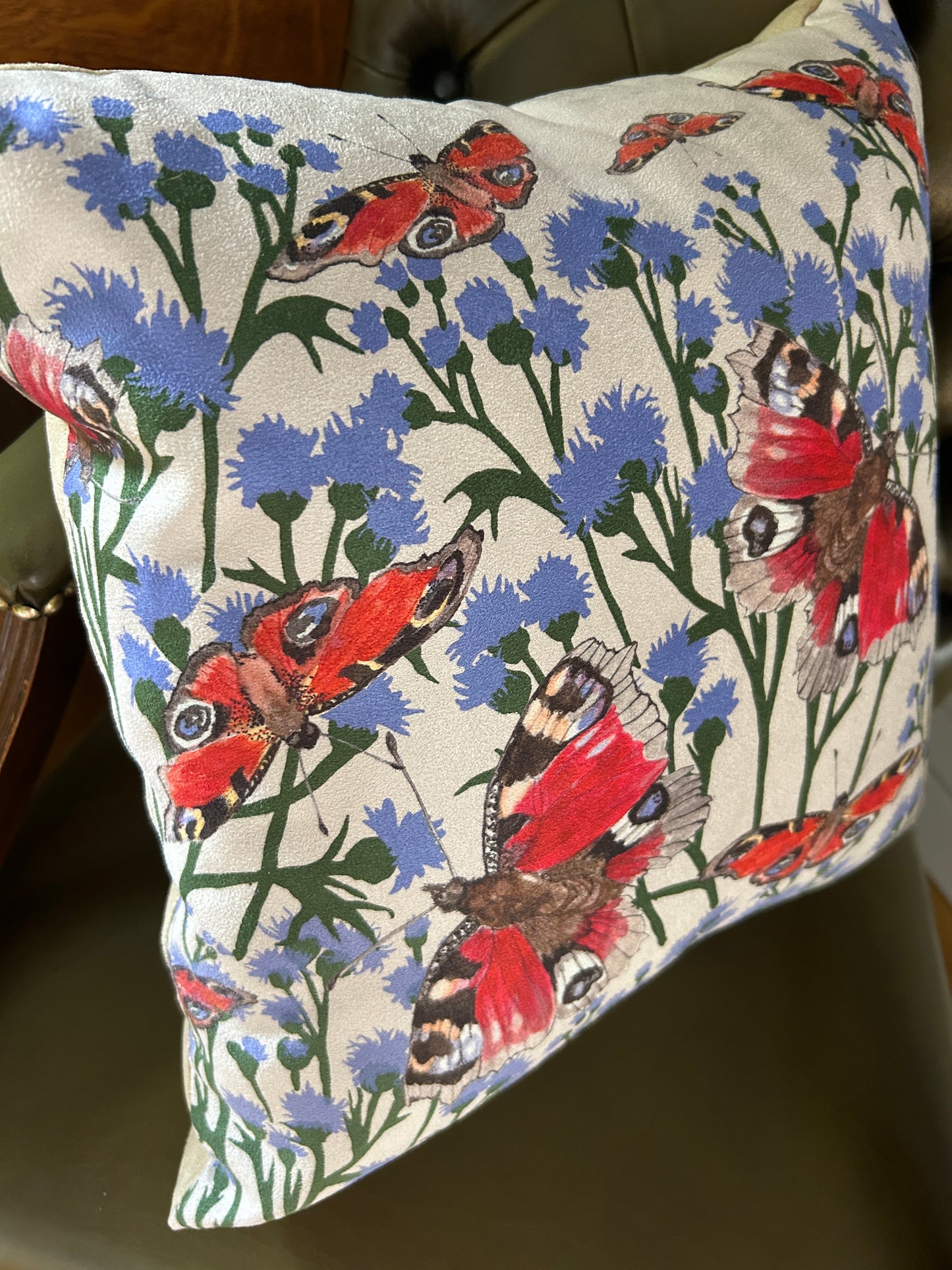Cushion with scottish peacock butterflies and thistle design on a taupe background