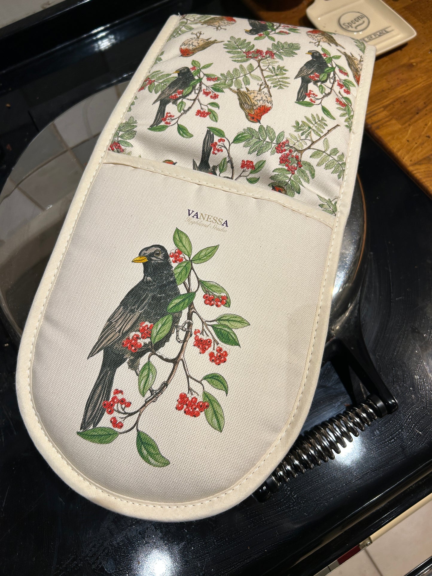 Black bird oven glove on a range cooker lid.