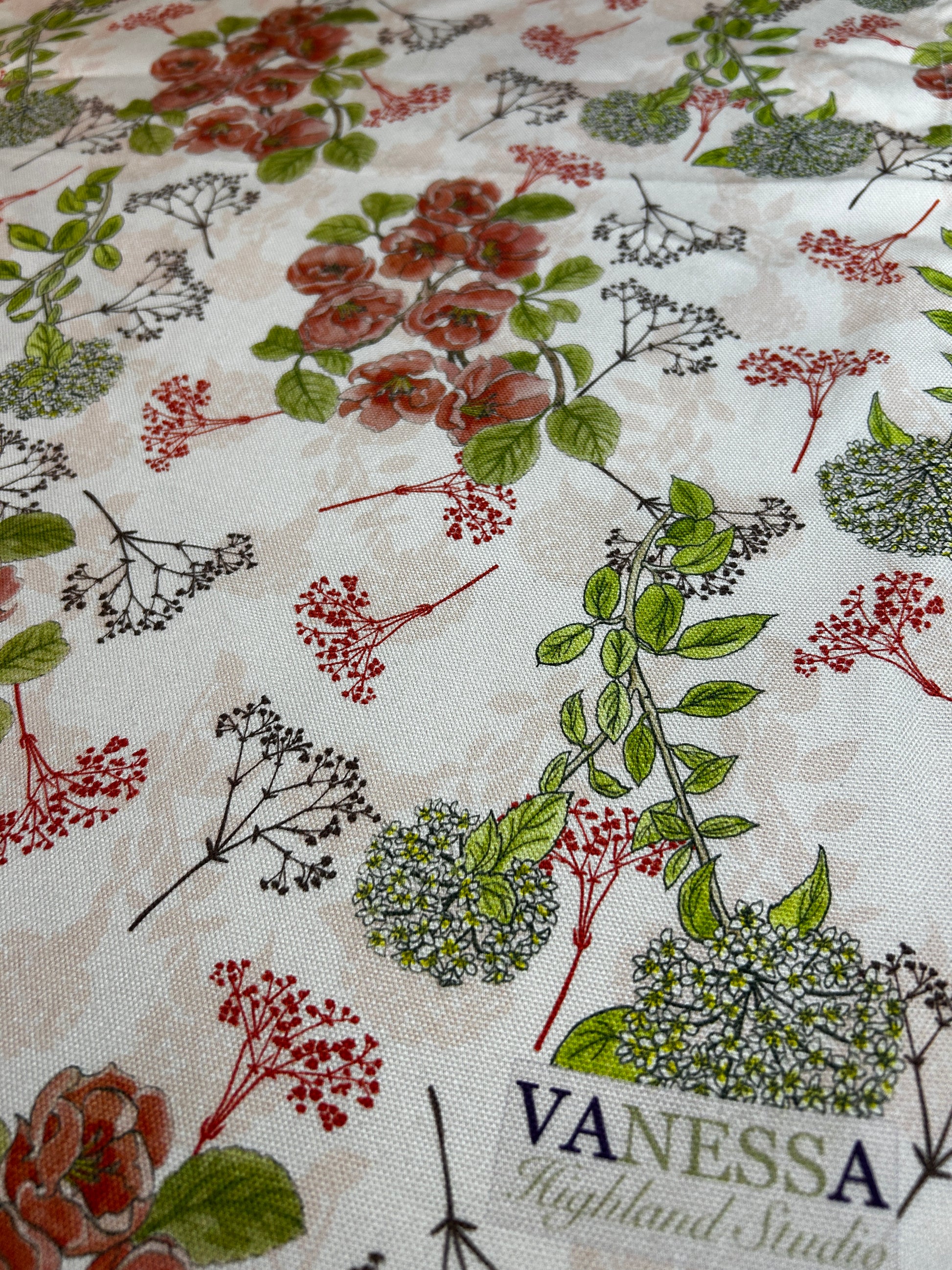 CLose up of floral fabric with Quince flower and Viburnum flower design and Vanessa Logo