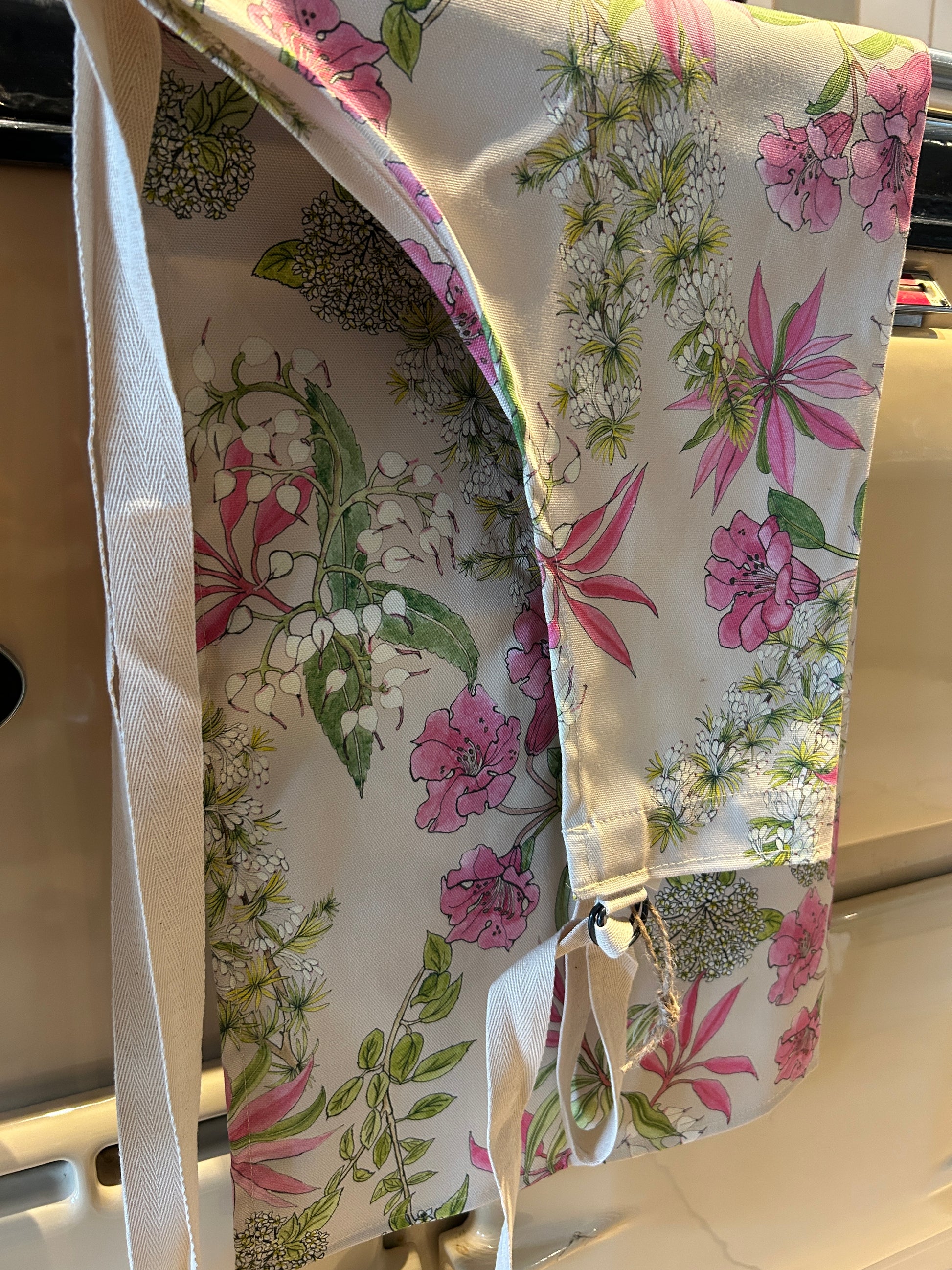 Floral apron of pink Rhododendron flowers hanging on a range cooker