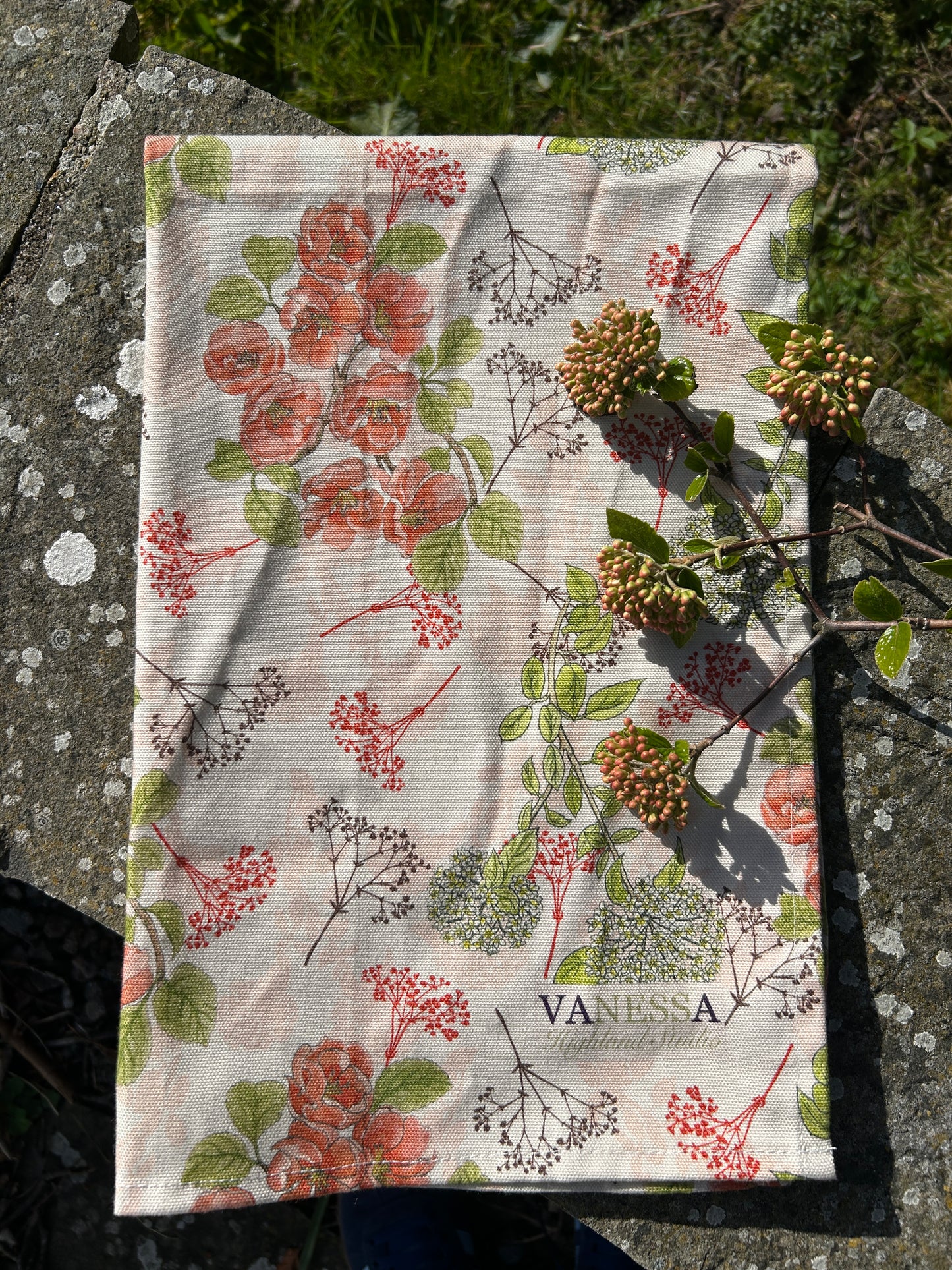 Soft floral designed tea towel with berries on a rustic wall