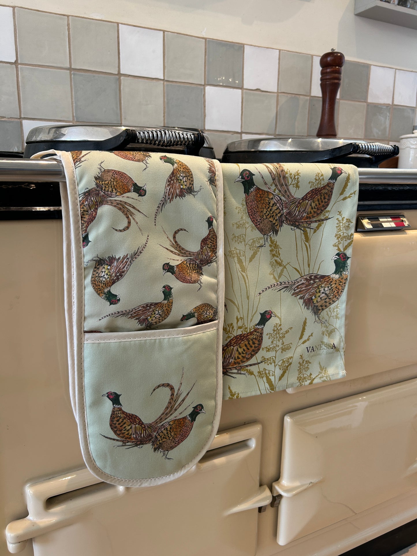 mint green oven glove and tea towel with pheasant design, hanging on a range cooker rail