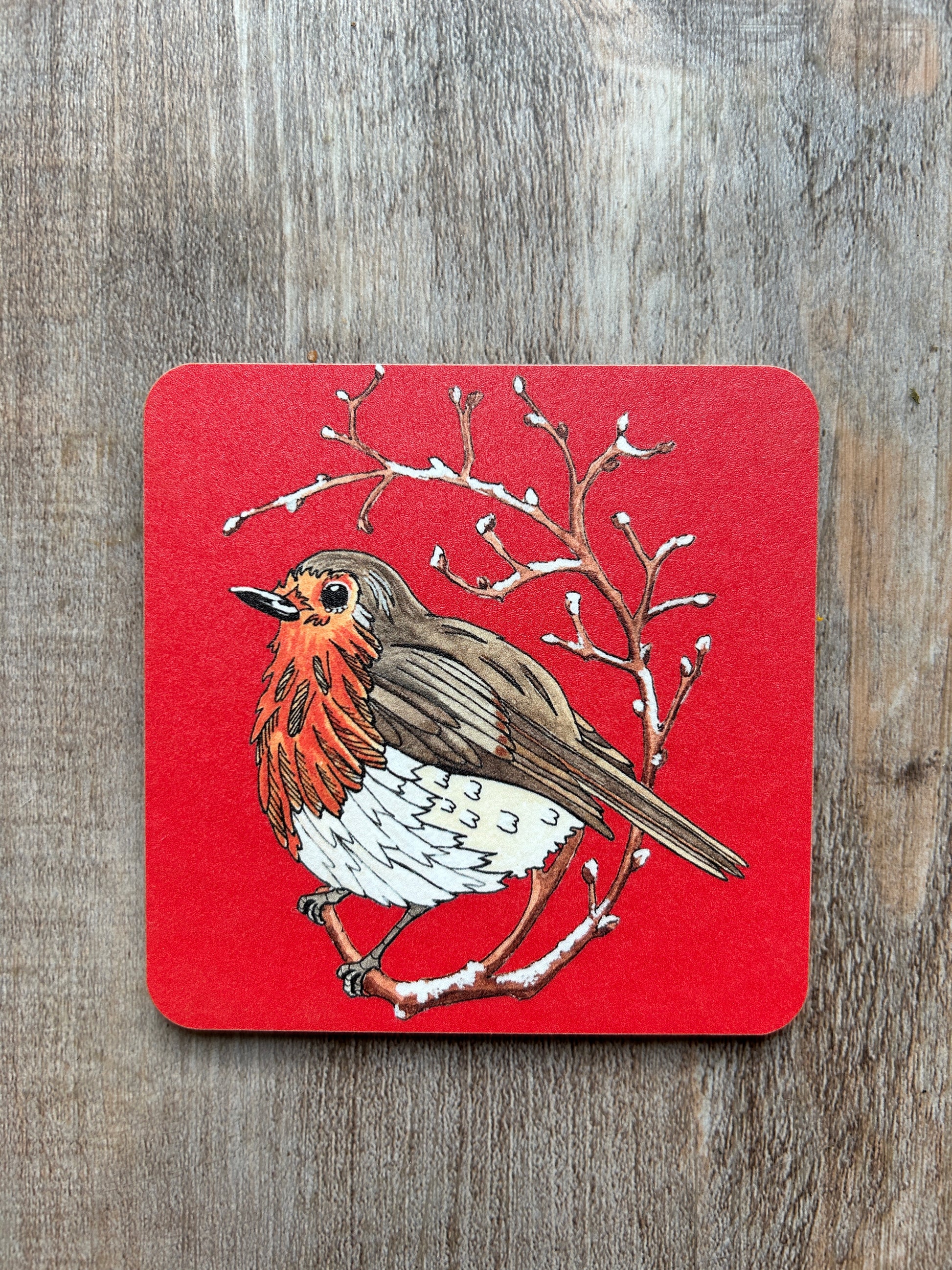 Illustration of a fluffy red robin on a frosty branch. Printed on a red coaster