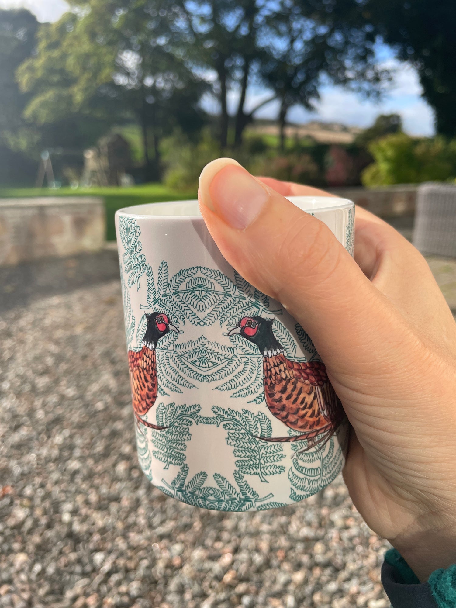 ceramic mug with pheasant fern design , held in an hand