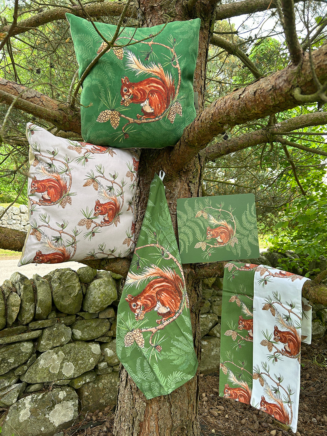 Selection of home accessory pieces in red squirrel design, displayed on the branches of a Scots Pine tree