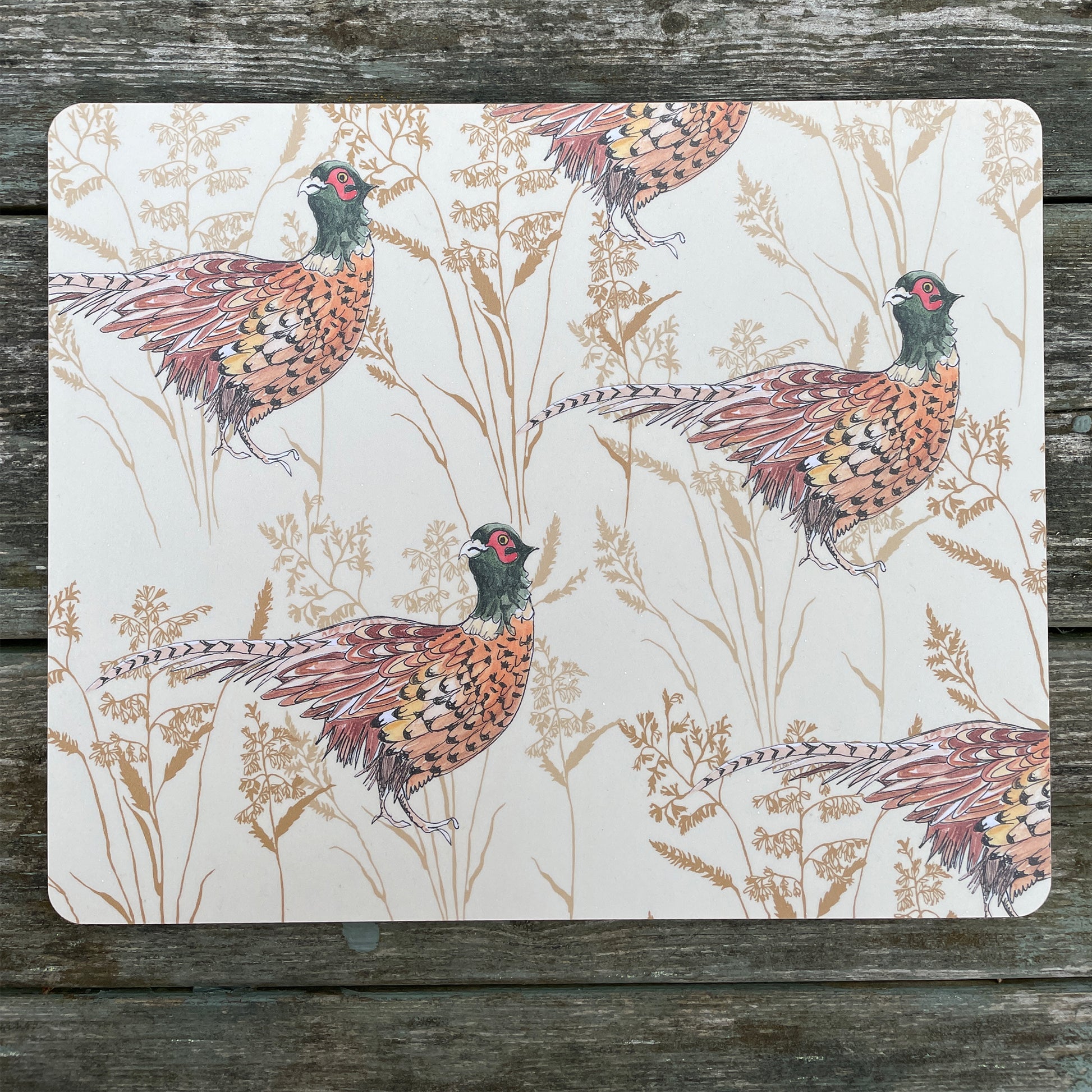 cream placemat with pheasant and grass illustration, on rustic table top