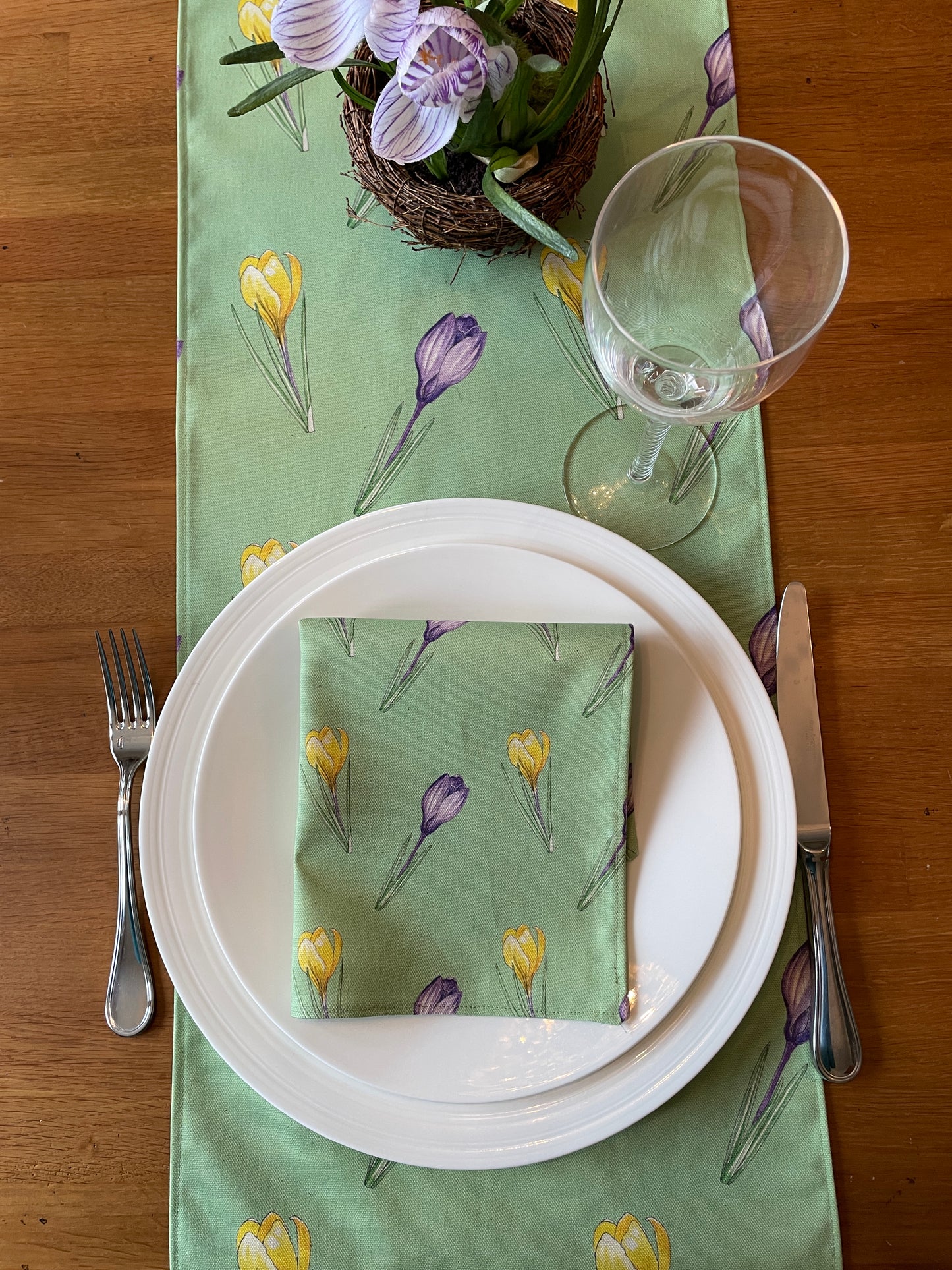 Place setting laid with crocus design cotton napkin and table runner in pale green.