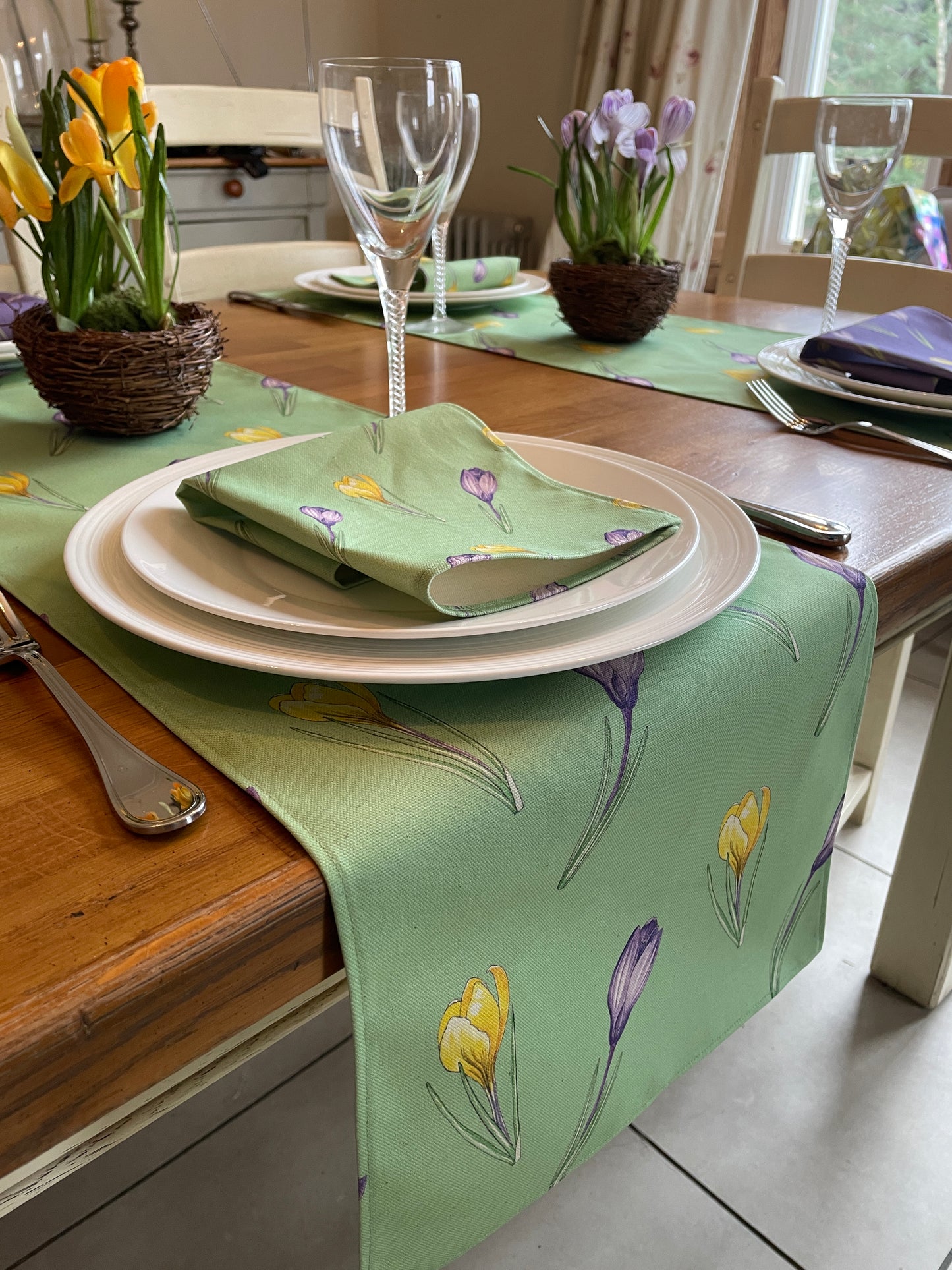 Short green crocus table runner with white crockery place setting and matching green napkin in Crocus flower design
